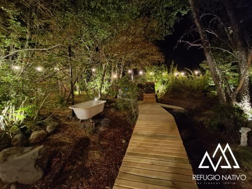 a bath tub sitting on a wooden walkway at night at Refugio Nativo in Nevados de Chillan