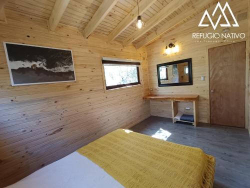 a bedroom with a bed and a desk in a room at Refugio Nativo in Nevados de Chillan