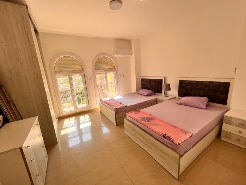 two beds in a room with two windows at Luxury Inn 3BR Amazing view in Madinaty B2 in Madinaty