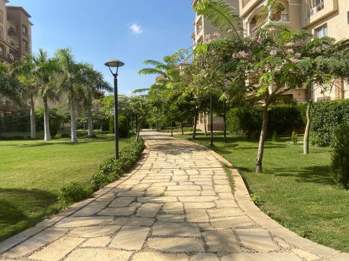 a cobblestone path in a park with palm trees at Luxury Inn 3BR Amazing view in Madinaty B2 in Madinaty