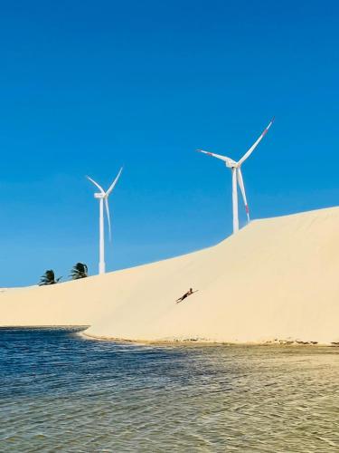 a beach with three windmills on a sand hill at Pousada Recanto das Flores in Praia de Moitas