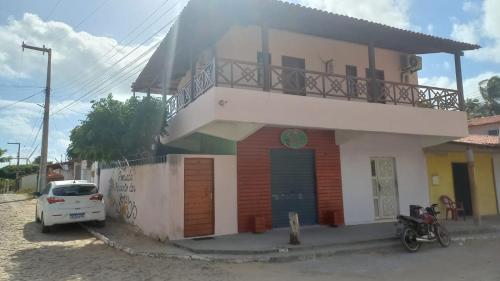 a house with a car parked in front of it at Pousada Recanto das Flores in Praia de Moitas