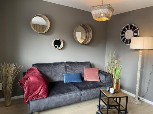 ein Sofa mit Kissen darauf in einem Wohnzimmer mit Spiegeln in der Unterkunft Gästehaus Wind und Meer in Norddeich