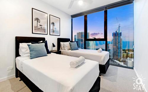two beds in a room with a large window at 3 Bedroom Private Apartments at Casino - Q Stay in Gold Coast