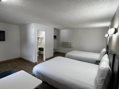 a hotel room with two beds and a table at Motel 6-Orange, CA - Anaheim in Anaheim