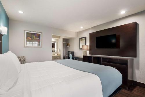 a bedroom with a white bed and a flat screen tv at SureStay Hotel Laredo by Best Western in Laredo