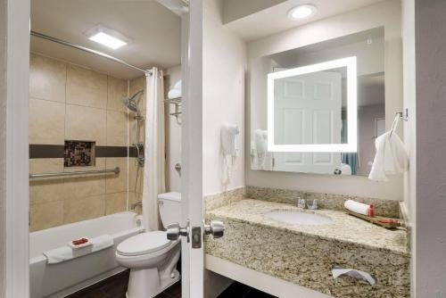 a bathroom with a sink and a toilet and a mirror at SureStay Hotel Laredo by Best Western in Laredo