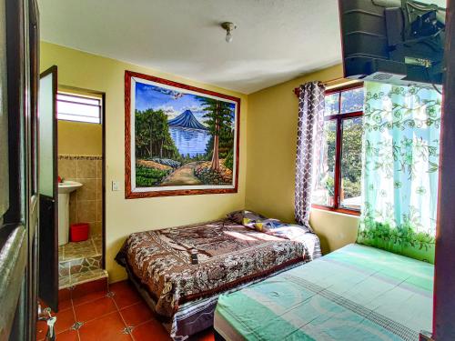 a bedroom with two beds and a painting on the wall at Casa Argentina in San Juan La Laguna