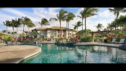 a large swimming pool with palm trees and a house at Summer Special! Hilton Pool Pass included! in Waikoloa