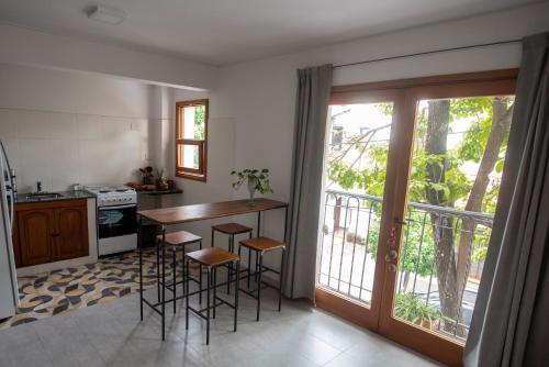 cocina con mesa y taburetes y balcón en Lapacho Amarillo, departamento turístico Salta en Salta