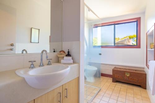 uma casa de banho branca com um lavatório e um WC em Dreamtime Belongil - house opposite the beach em Byron Bay