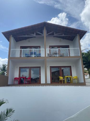 a house with colorful chairs in front of it at De Olho no Mar A única pousada de frente para o mar em Paracuru in Paracuru