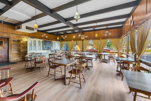 a restaurant with wooden tables and chairs and windows at Plainsman Motel in Forbes