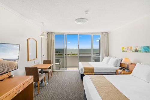 a hotel room with two beds and a balcony at Cairns Harbourside Hotel in Cairns