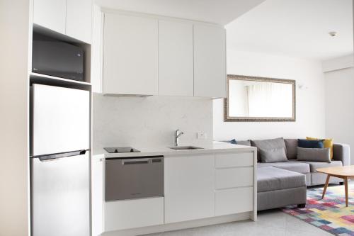 a kitchen with white cabinets and a gray couch at Netanya Noosa Beachfront Resort in Noosa Heads