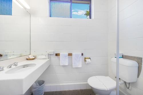 a white bathroom with a toilet and a sink at Plainsman Motel in Forbes