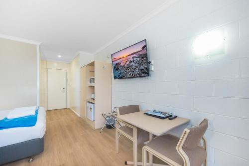 a small room with a table and a bed and a tv at Plainsman Motel in Forbes