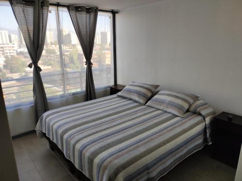 1 dormitorio con cama con sábanas a rayas y ventana en Departamento arriendo diario, en Santiago