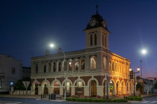 a large building with a clock tower at night at Plainsman Motel in Forbes