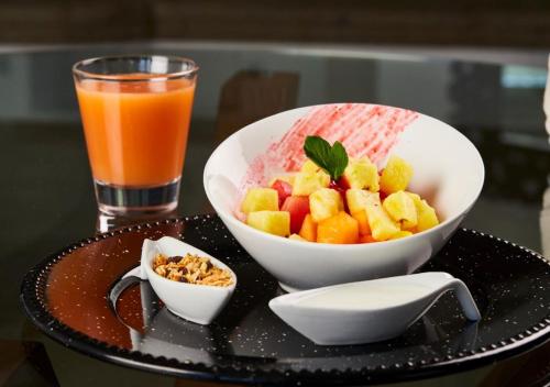 a tray with a bowl of fruit and a glass of orange juice at Hotel Boutique de Cantera Y Plata in Taxco de Alarcón