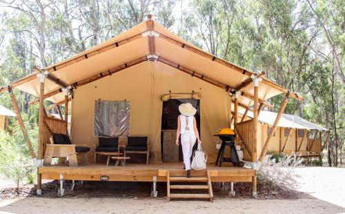 a woman standing in front of a small yellow tent at Koondrook Glamping Retreat in Koondrook