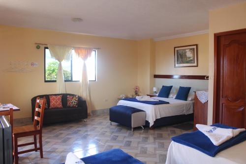 a hotel room with two beds and a chair at Hostal Romy in Puerto Baquerizo Moreno