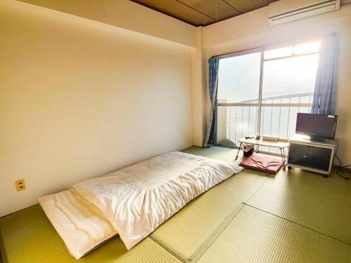 a bedroom with a bed and a tv and a window at Weekly Hotel Kokura in Kitakyushu