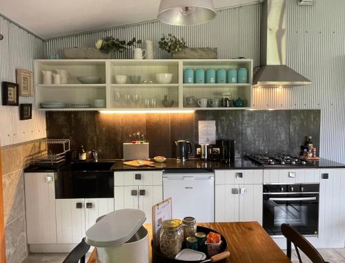 a kitchen with white cabinets and a wooden table at The Studio - Yarra Valley in Yarra Glen