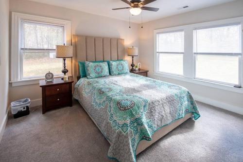 1 dormitorio con 1 cama con colcha verde y 2 ventanas en The Bike Path House! Cozy 2 BR w/ Fireplace, en Charles City