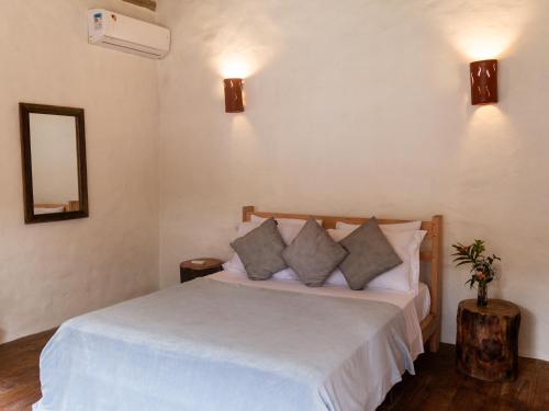 a bedroom with a bed with white sheets and pillows at Villa Sagui Trancoso in Trancoso