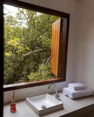 a bathroom mirror with a sink and a window at Villa Sagui Trancoso in Trancoso
