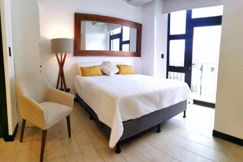 Tijax 10 apartamento en zona 10 في غواتيمالا: غرفة نوم بسرير وكرسي ومرآة