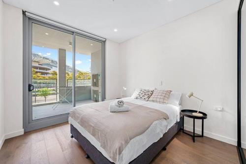 a white bedroom with a bed and a large window at Commodious 2 Bedroom APT in OP in Sydney