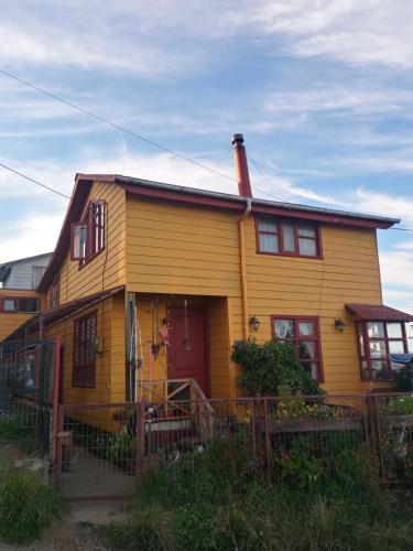 żółty dom z czerwonymi drzwiami w obiekcie Esencia Chilota w mieście Ancud