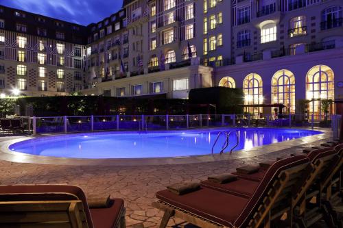 - une grande piscine en face d'un bâtiment la nuit dans l'établissement Hôtel Barrière Le Royal Deauville, à Deauville