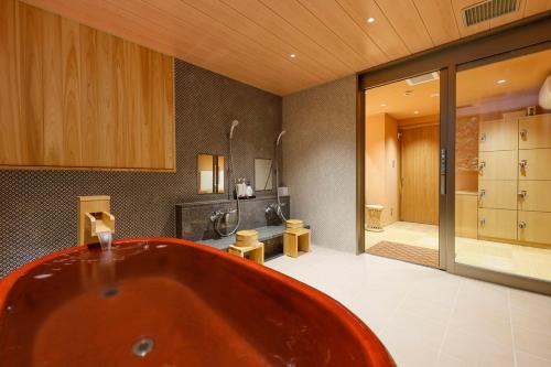 un ampio bagno con vasca e doccia di Yuraku Kinosaki Spa & Gardens a Toyooka