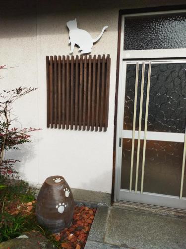 una porta d'ingresso di una casa con un gatto sul muro di Happy Neko a Beppu