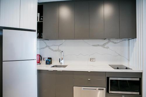 a kitchen with gray cabinets and a white refrigerator at Netanya Noosa Beachfront Resort in Noosa Heads