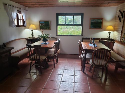 a dining room with tables and chairs and a window at Sitio Santa Clara in Teresópolis