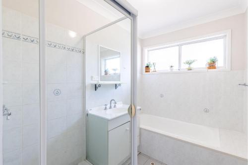 a white bathroom with a shower and a sink at 110 Catalina Close so close to the water in Shoal Bay