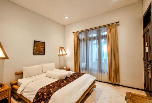 a bedroom with a bed and a large window at Rumah Mertua Heritage in Yogyakarta