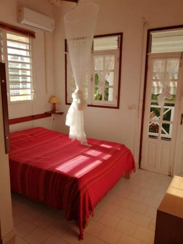 a bedroom with a red bed with a veil on it at Bungalow les hibiscus in Saint-François