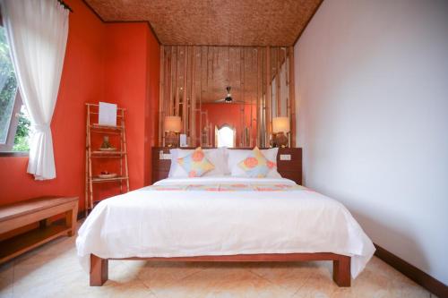 a bedroom with a large white bed with orange walls at Gayatri in Ubud