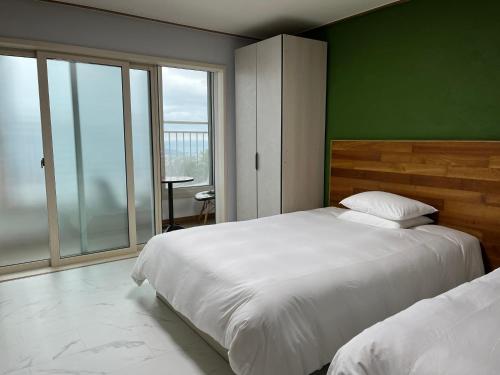 um quarto com 2 camas e uma parede verde em Hill Hotel em Jeju