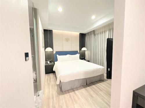 a bedroom with a white bed and a blue headboard at 台南星鑽國際商旅 Hua Hotel in Tainan