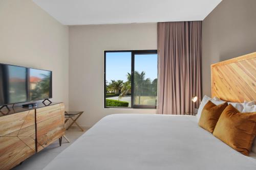 een witte slaapkamer met een groot bed en een televisie bij Gold Coast Aruba - Aurum Collection in Malmok
