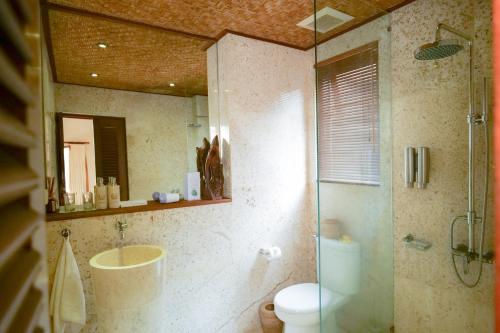 a bathroom with a shower and a toilet and a mirror at Gayatri in Ubud