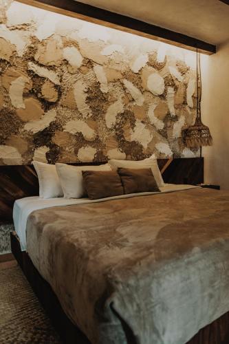 a bedroom with a large bed with a wall at BOA BOA Bacalar in Bacalar