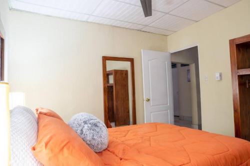 1 dormitorio con cama de color naranja y espejo en COZY Fully equipped private apartment, en Chimaltenango
