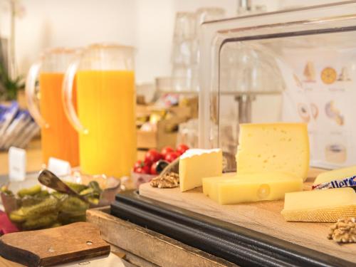 a cutting board with cheese and a glass of orange juice at Hotel Bernerhof Grindelwald in Grindelwald